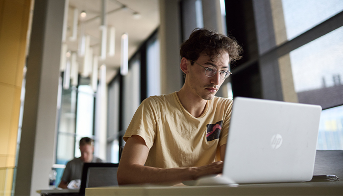 Male student working on computer in library