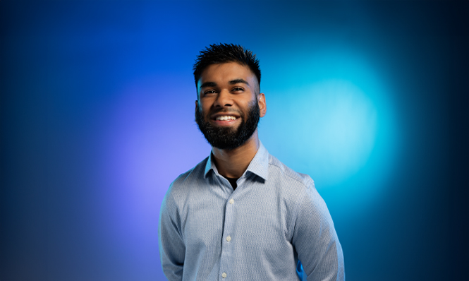 Smiling male student, standing against a coloured background